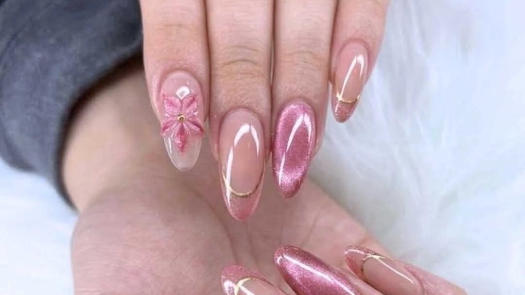 Pink cat-eye and gold-lined French almond nails with a 3D pink flower