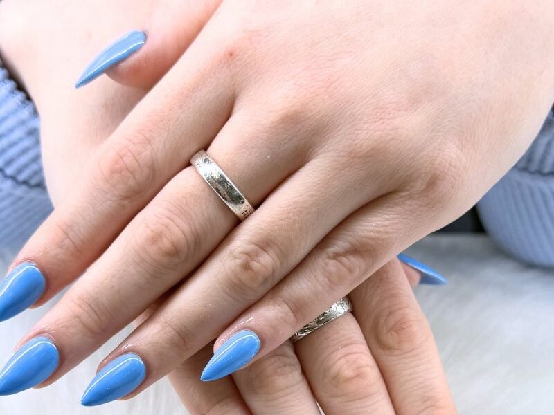 Glossy periwinkle blue almond nails on a white fur backdrop