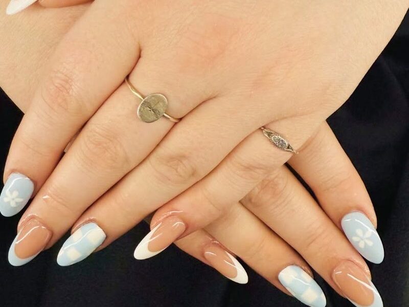 Almond nails with white French tips, baby-blue checkerboard and painted white flowers